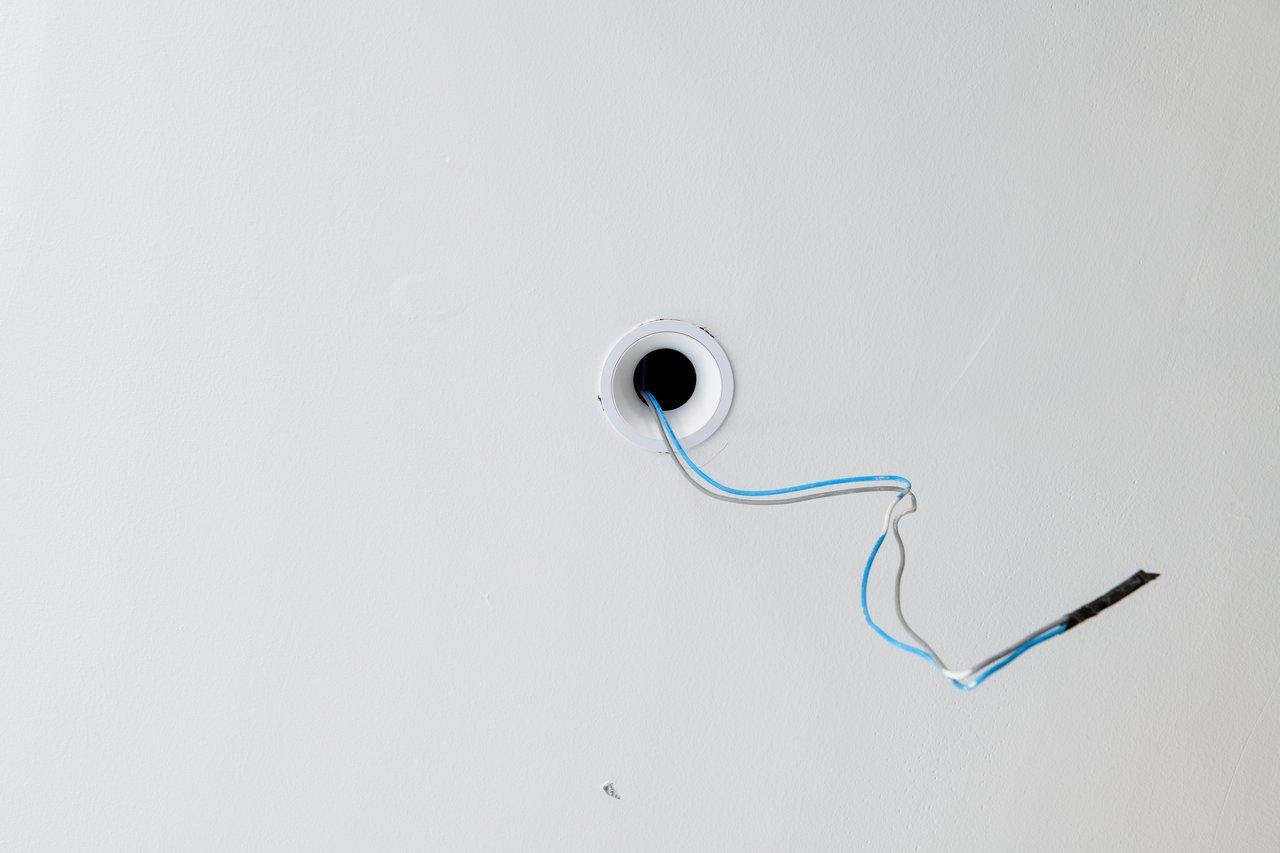 Détail du câblage électrique pour l'installation d’un variateur de lumière, visible dans une boîte d’encastrement.