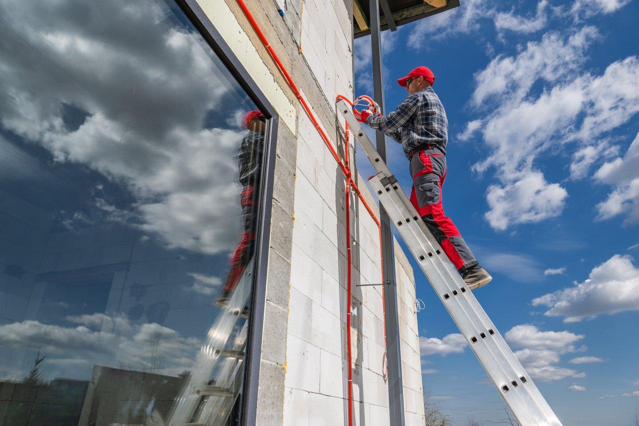 Échelle télescopique en aluminium déployée sur sol stable, sécurité renforcée pour une installation extérieure fiable.