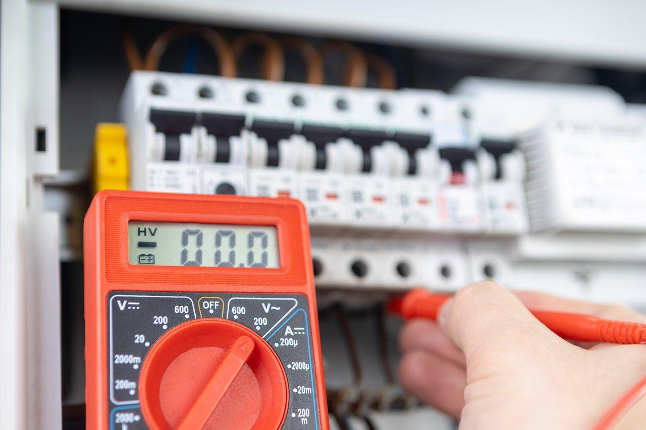 Électricien effectuant un test de déclenchement manuel sur un disjoncteur différentiel avec bouton TEST.