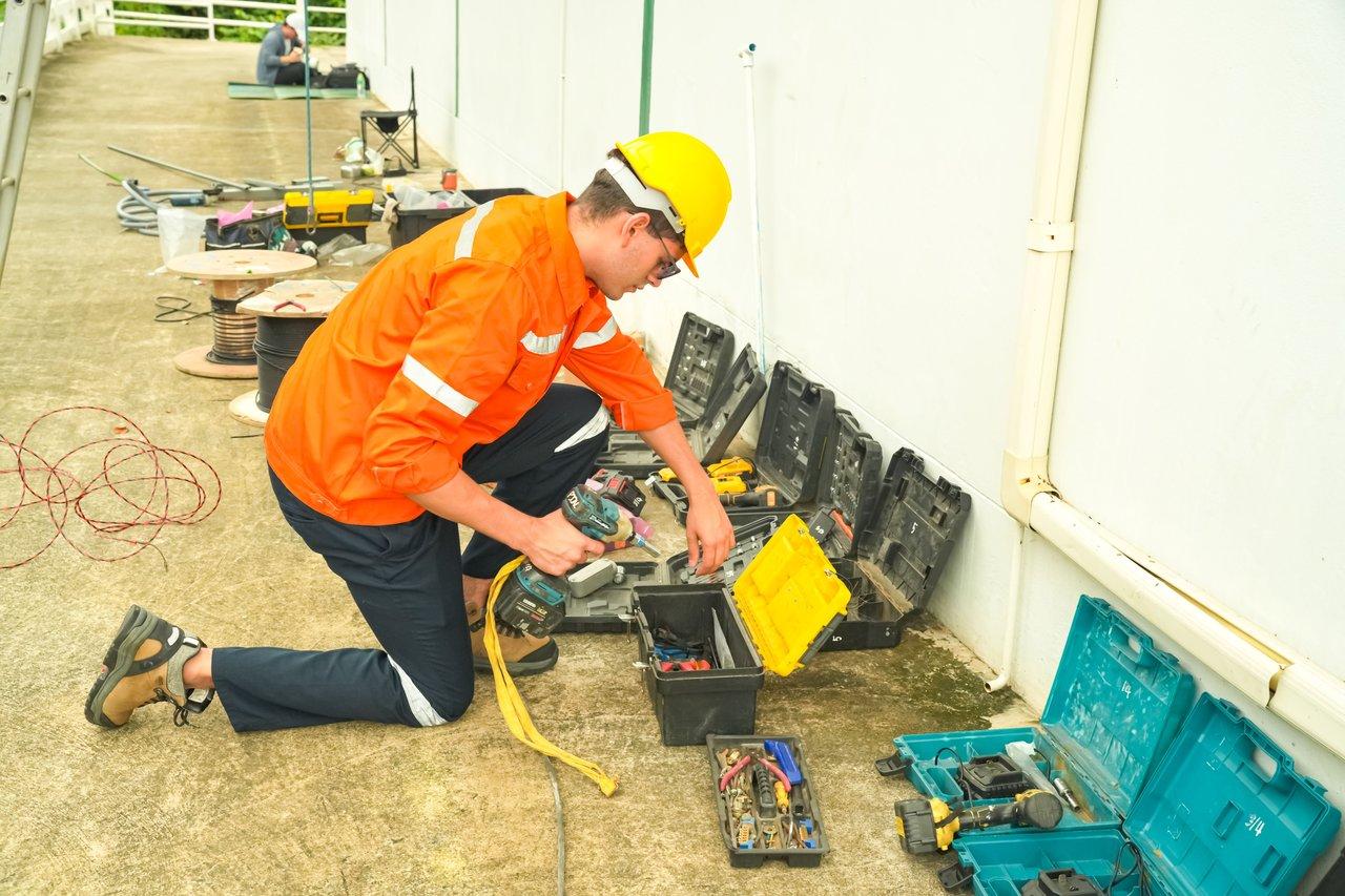 Électricien en tenue de sécurité utilisant un détecteur de tension pour une intervention sécurisée sur chantier électrique.