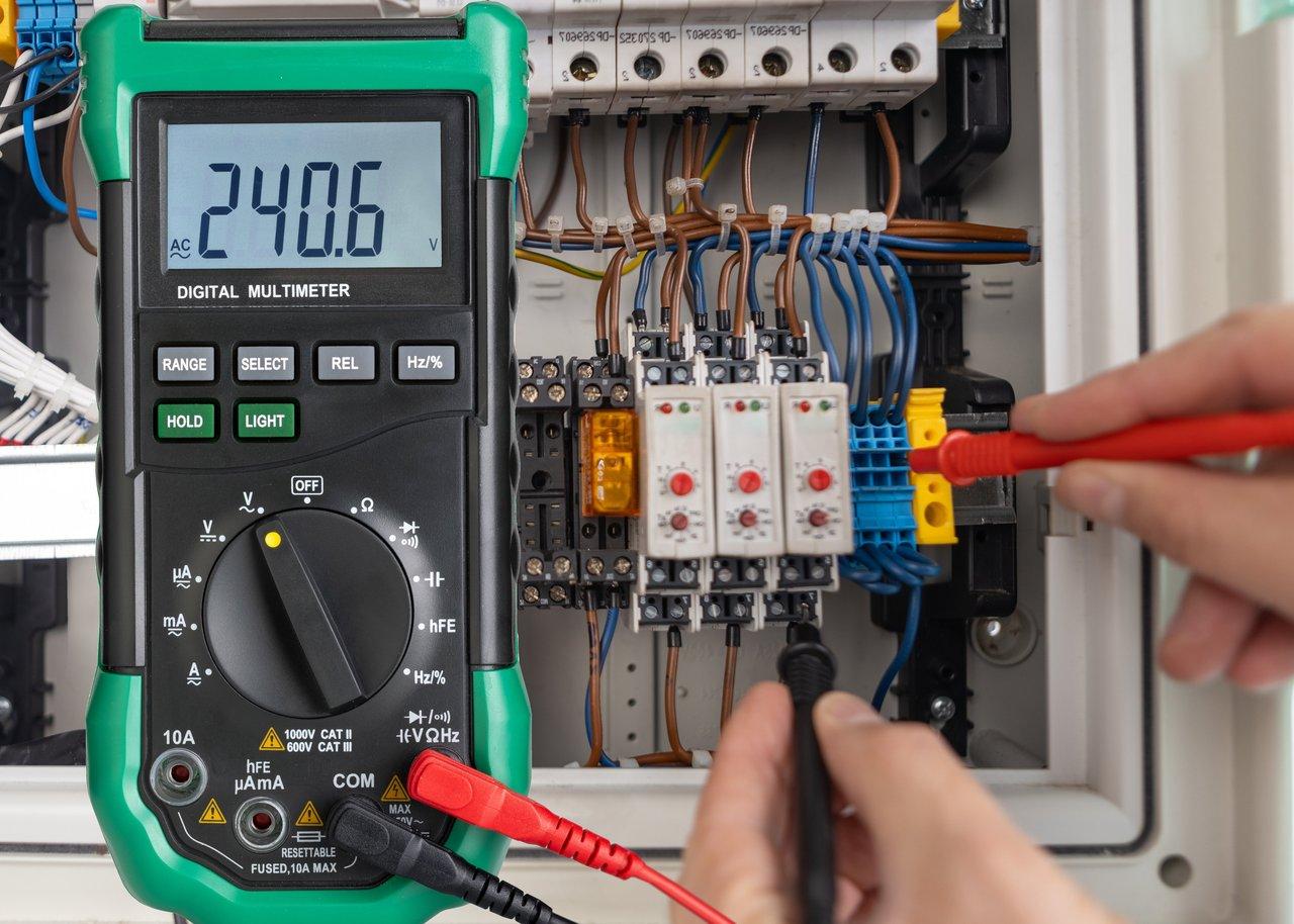 Électricien utilisant un détecteur de tension multifonctions ergonomique pour assurer une sécurité optimale sur le chantier.
