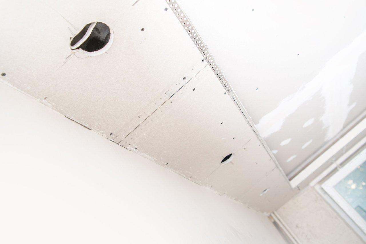 Installation d’un plafonnier avec suspension dans un plafond en placo, utilisant des chevilles Molly pour une fixation sécurisée.