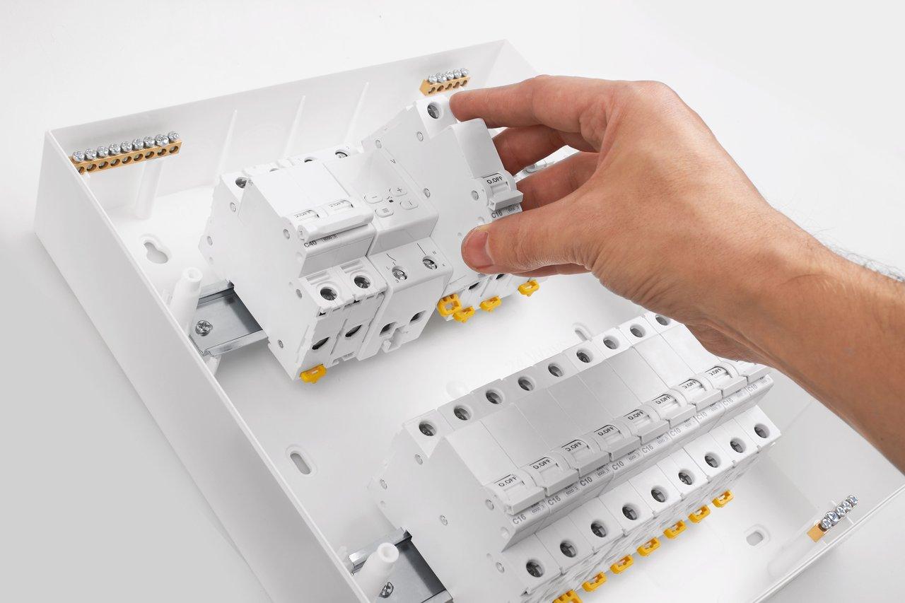 Installation professionnelle d'un disjoncteur modulaire sur rail DIN dans un tableau électrique.