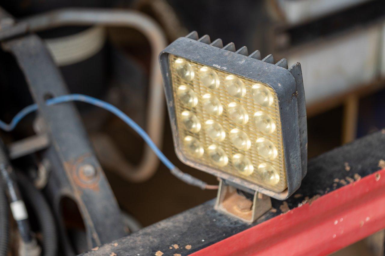 Lampe de chantier LED industrielle avec cage métallique, pied stable et protection IP64 pour une utilisation robuste.