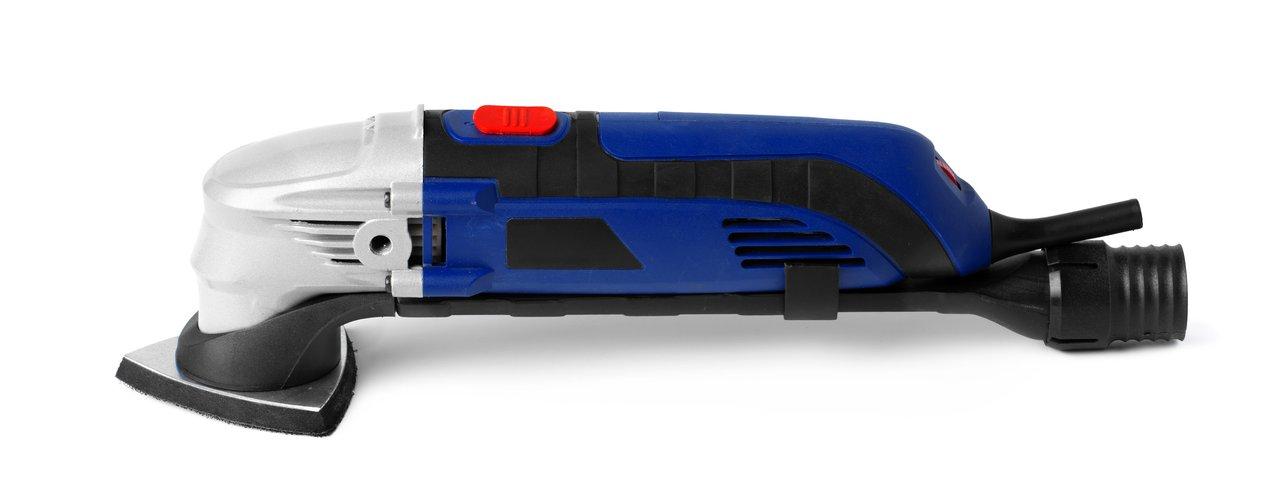 L'outil multifonction oscillant en action sur plaque de plâtre avec accessoires variés pour une coupe précise.