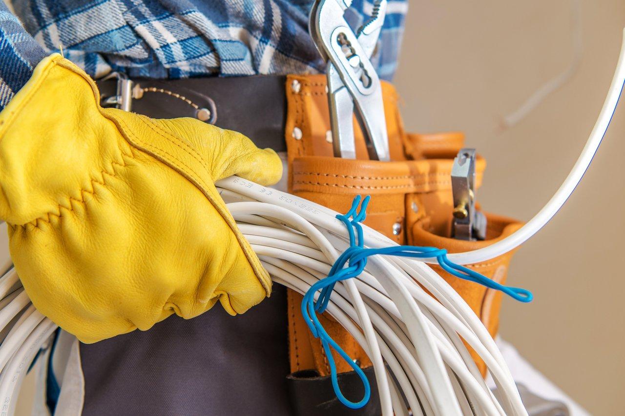 Ouvrier équipé de gants isolants et d’un équipement de protection complète lors d’une intervention électrique.