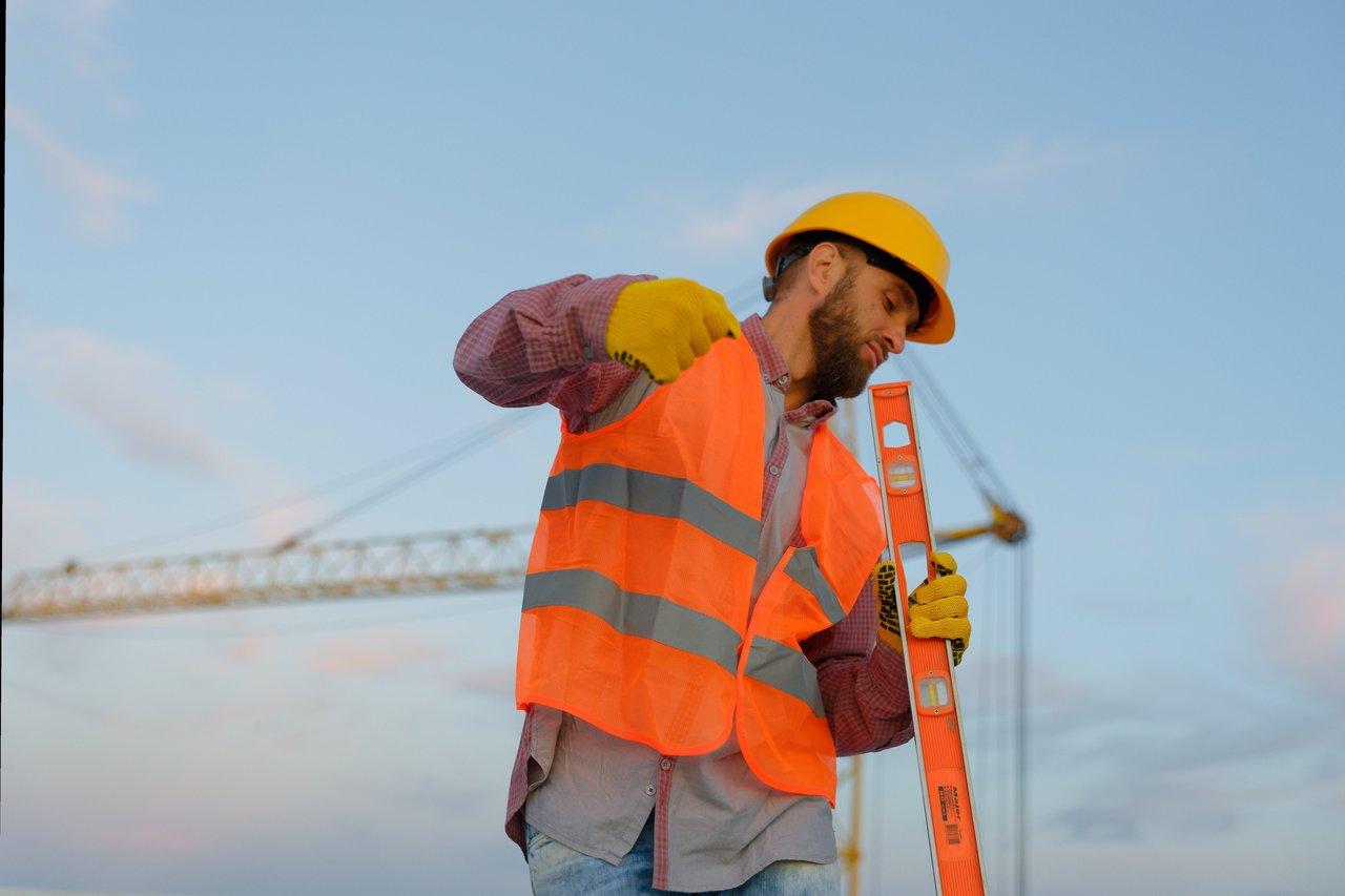 Ouvrier portant équipement antidérapant et vêtements techniques sur chantier automnal pluvieux, garantissant sa sécurité.