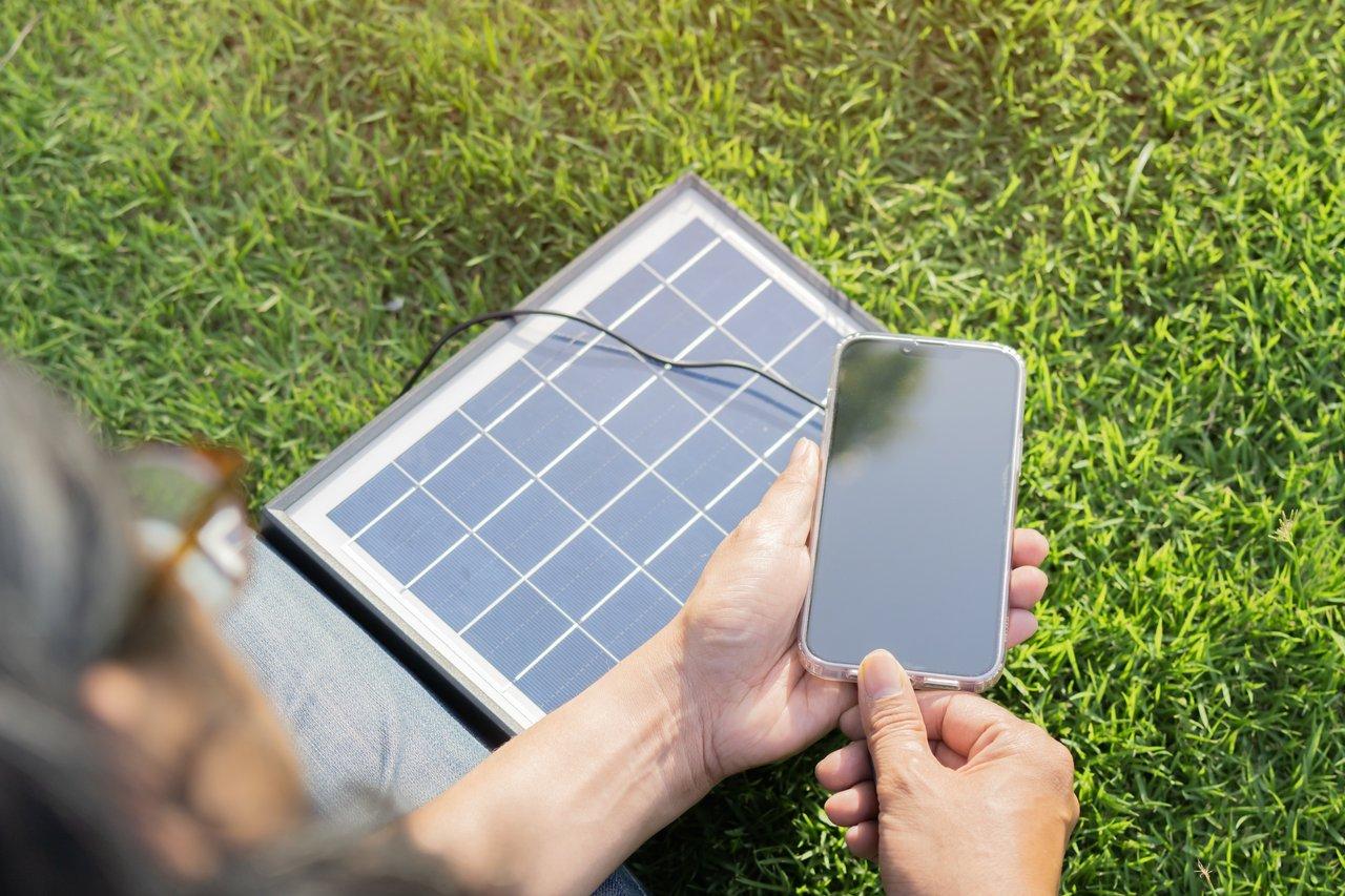 Panneau solaire flexible mobile en action lors d'une intervention pour charger un smartphone en extérieur.