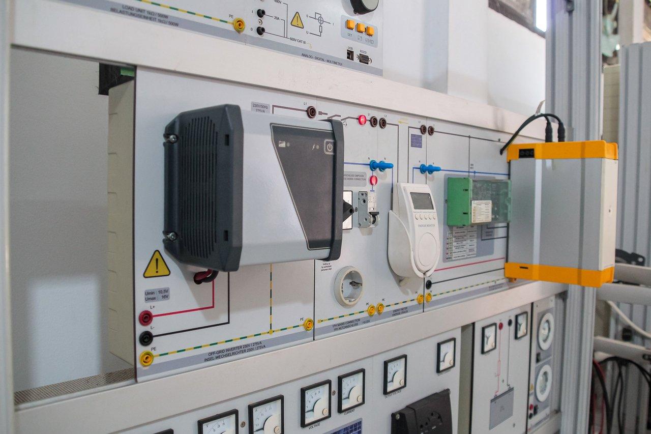 Schéma illustrant le calcul de la somme pondérée des intensités pour déterminer le nombre de disjoncteurs nécessaires dans un atelier de 100 m², selon la charge électrique.