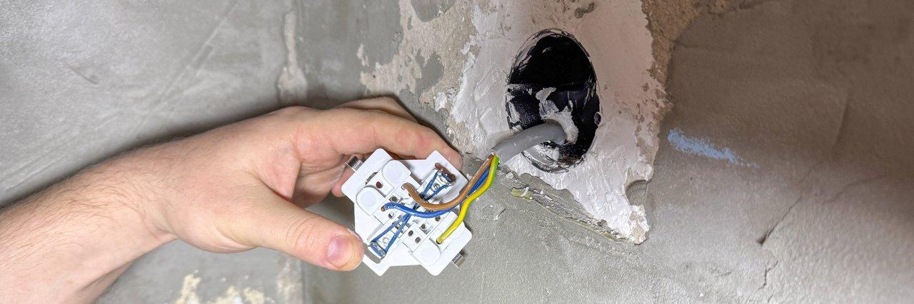 Technicien électrique en formation effectuant une inspection thermique d'un tableau électrique pour la maintenance préventive.