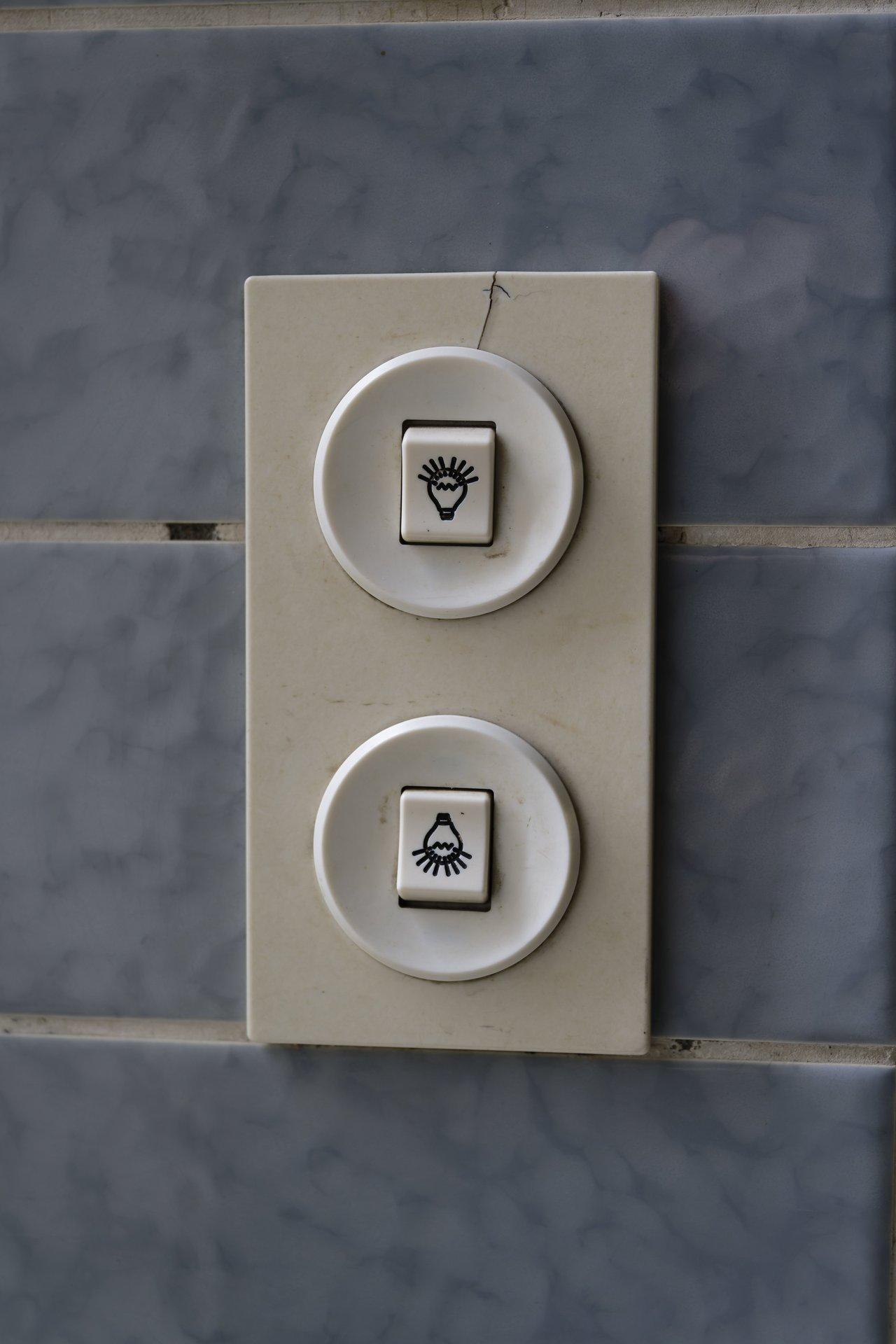 Types de variateurs de lumière vintage avec boutons et molette sur carreaux bleus, pour un contrôle lumineux élégant.