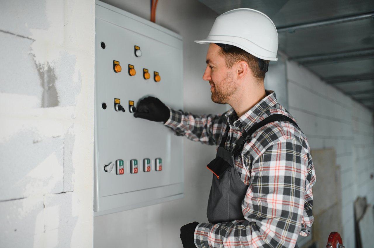 Un électricien installant un verrouillage sécurisé sur une armoire électrique conforme aux normes NF C 15-100 lors d'une construction.