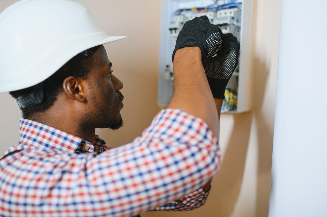 Un électricien installe une borne de recharge pour véhicule électrique dans une maison, assurant une connexion sécurisée.