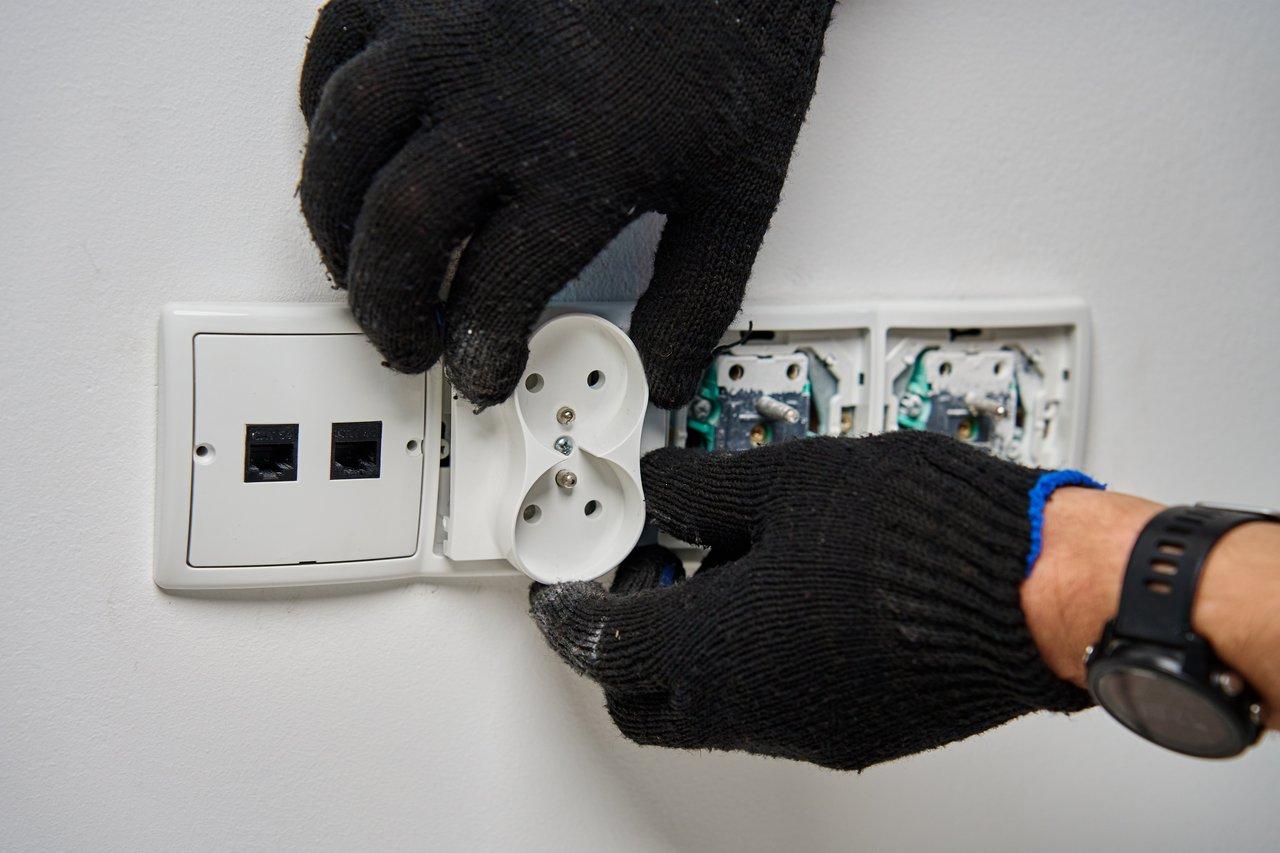 Un électricien portant des gants isolants mécaniques composites lors d'une intervention électrique sous tension.