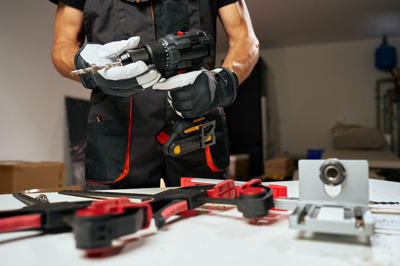 Un électricien utilisant une perceuse-visseuse sans fil brushless 18V dans un local technique bien éclairé.
