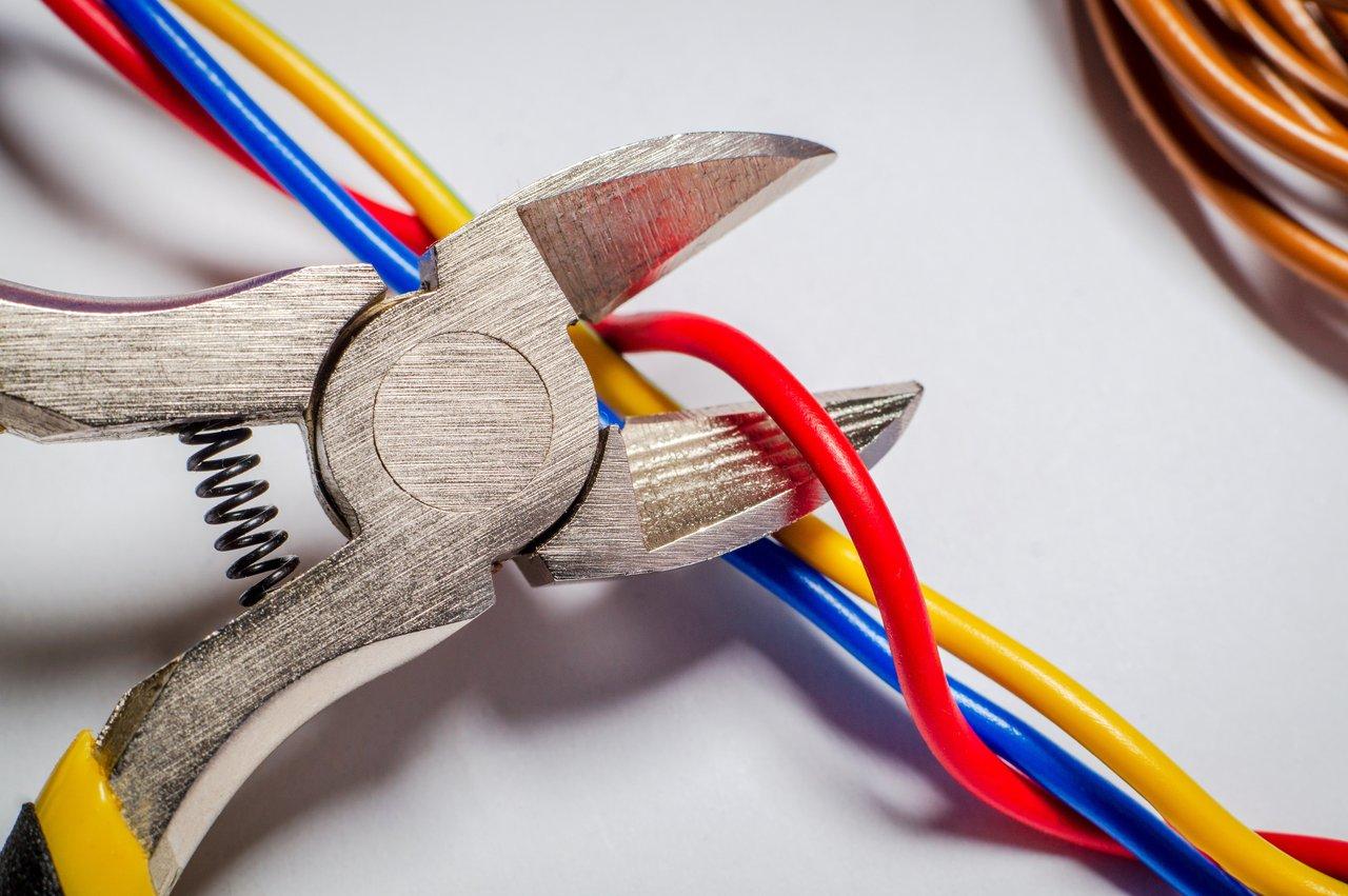 Un électricien utilisant une pince à dénuder automatique ergonomique pour préparer un câble électrique.