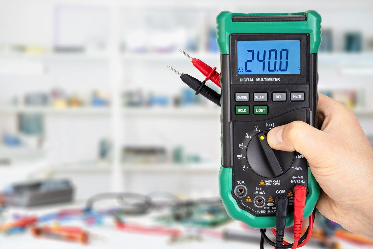 Un multimètre numérique Kaiweets en atelier professionnel, affichant des mesures précises de tension électrique.