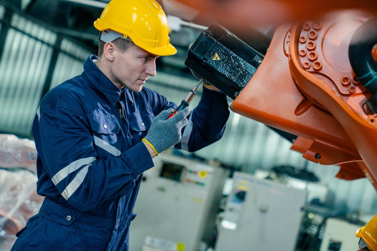 Un technicien change une lame d’outil oscillant en toute sécurité avec équipement de protection lors d'une maintenance industrielle.