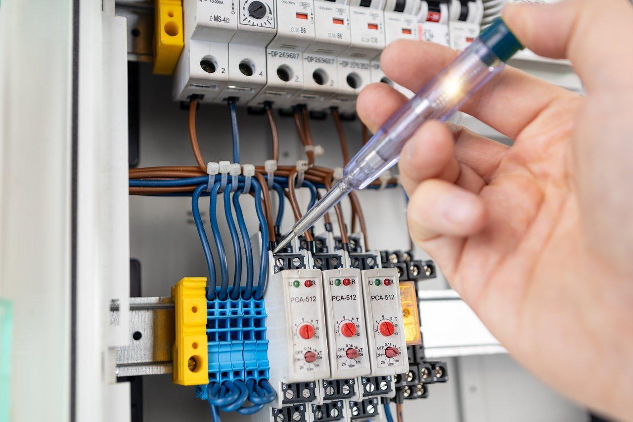 Un technicien effectue un test électrique précis sur un panneau de distribution pour garantir la conformité et la sécurité.