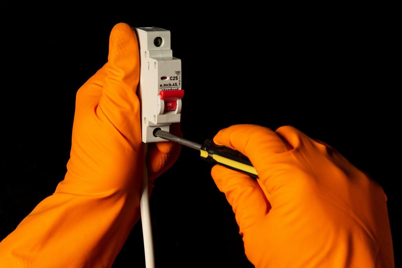 Un technicien portant des gants isolants lors d'une intervention sur un tableau électrique pour garantir la sécurité électrique.